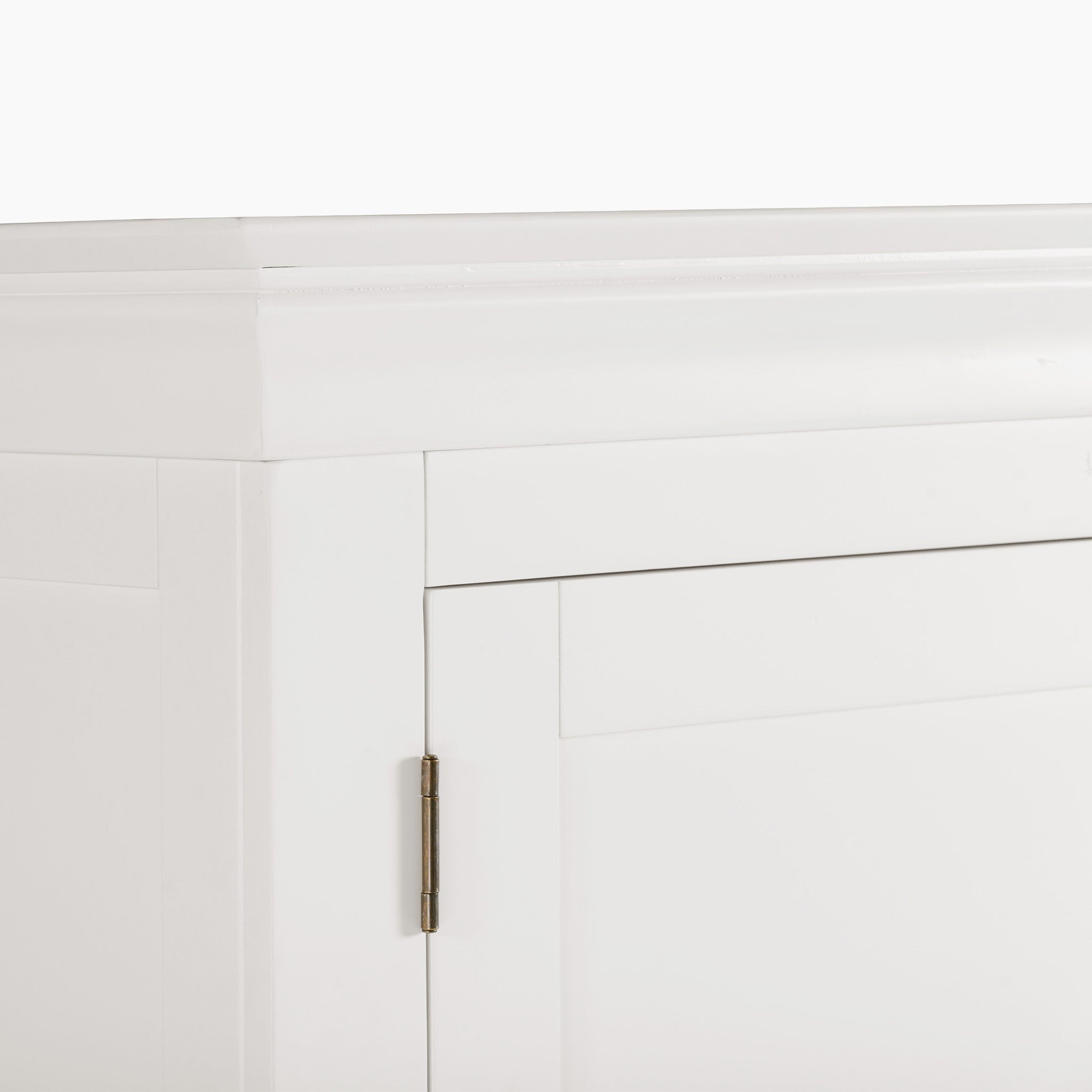 Close-up of a cabinet corner in Warm White with a visible hinge on the left side, featuring contemporary design elements inspired by the Chalbury Triple Wardrobe.