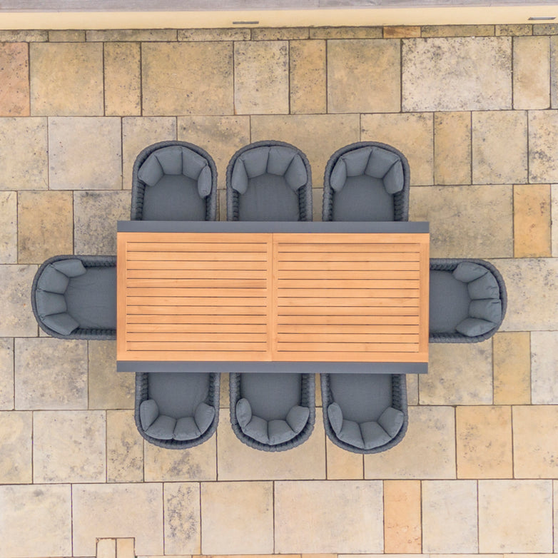 Top view of a Palma 8 Seat Rope Extending Teak Dining Set in Grey with six cushioned chairs on a large stone-tiled patio.