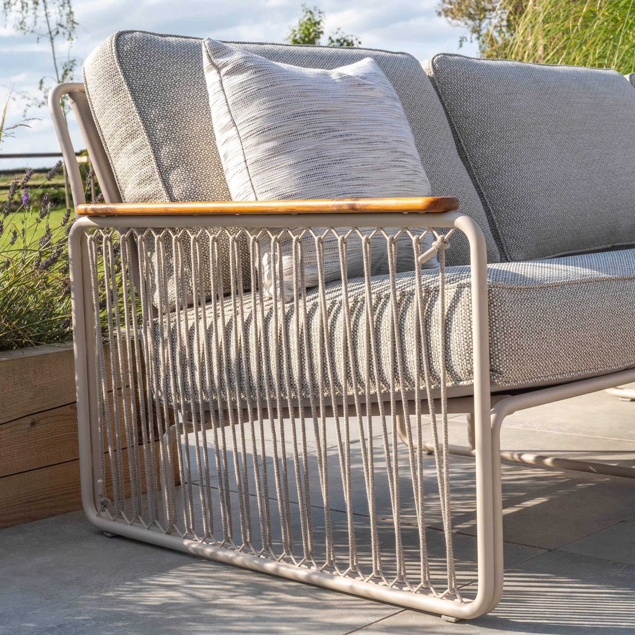 The Riviera Luxury Large Outdoor Corner Group Set in Latte features a stylish metal frame and hydrophobic rope weave design, complemented by teak armrests and beige cushions.