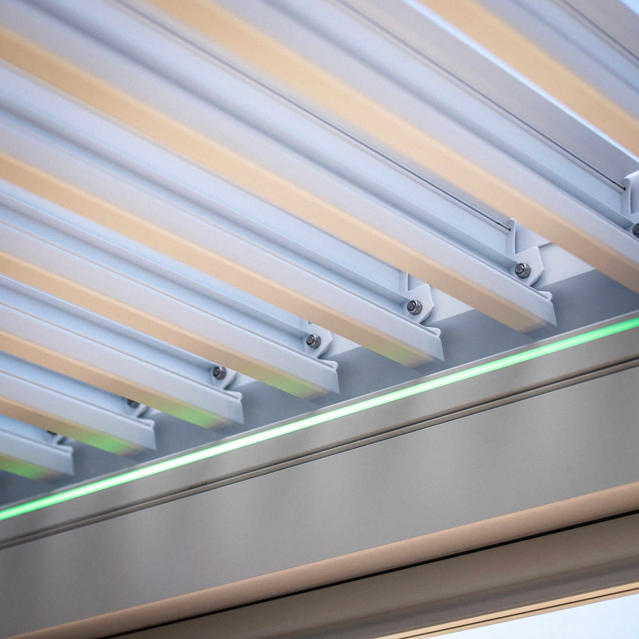 Close-up view of an architectural structure featuring modern metallic slats and a green light strip, reminiscent of the sleek design seen in the PergoSTET 3m x 3m Square Pergola with 3 Drop Sides and LED Lighting in White.