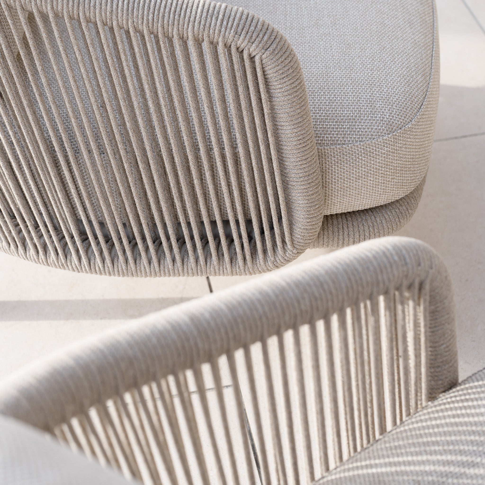 A close-up of the Dekota 3 Seat Rope Sofa Set, crafted with olefin rope weave and light fabric, placed on a tiled floor. Ideal for outdoor furniture enthusiasts seeking stylish comfort.