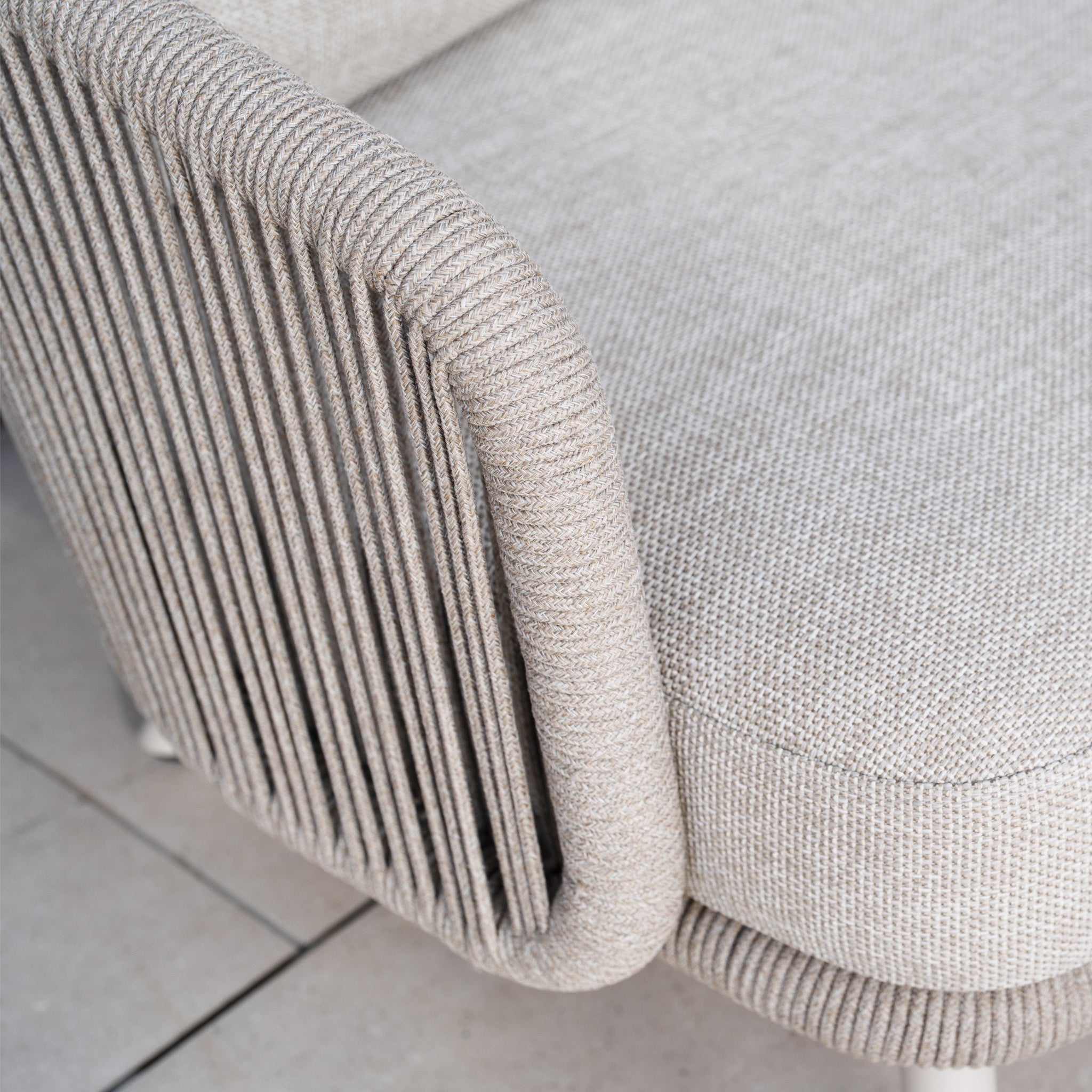 Close-up of a beige woven armchair with an olefin rope weave, ribbed texture, and rounded edges from the Dekota 3 Seat Rope Sofa Set in Fawn, elegantly placed on a tiled floor.