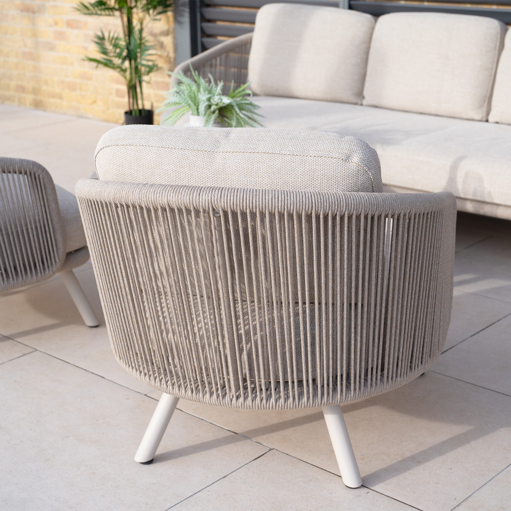 Outdoor chair with olefin rope weave and cushion, beautifully set on the patio beside the Dekota 3 Seat Rope Sofa Set with Coffee Tables and Footstool in Fawn and lush plants—ideal for your inviting outdoor furniture ensemble.