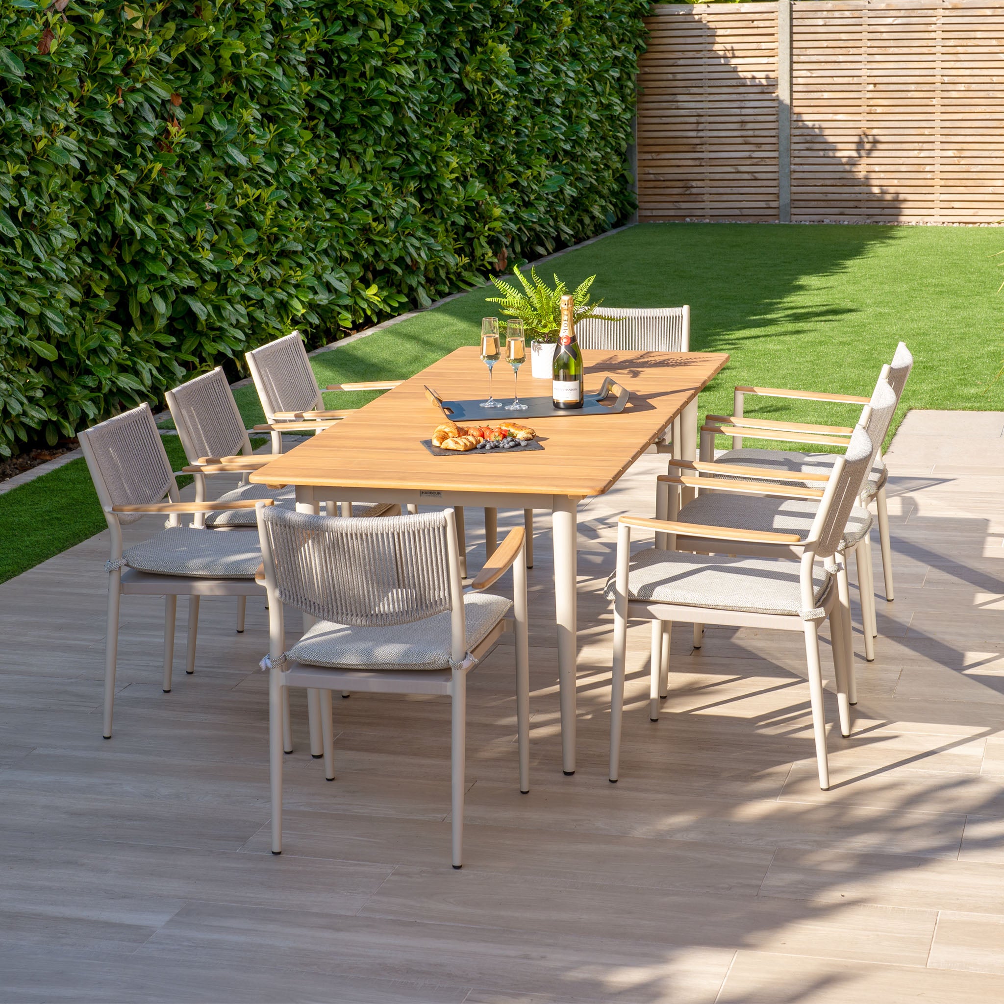 Dine outdoors in style with the Tellaro 8 Seat Rectangular Dining Set. Featuring a weather-resistant teak table in latte and comfortable seating for eight, it's perfect for enjoying wine and snacks amidst patio greenery.