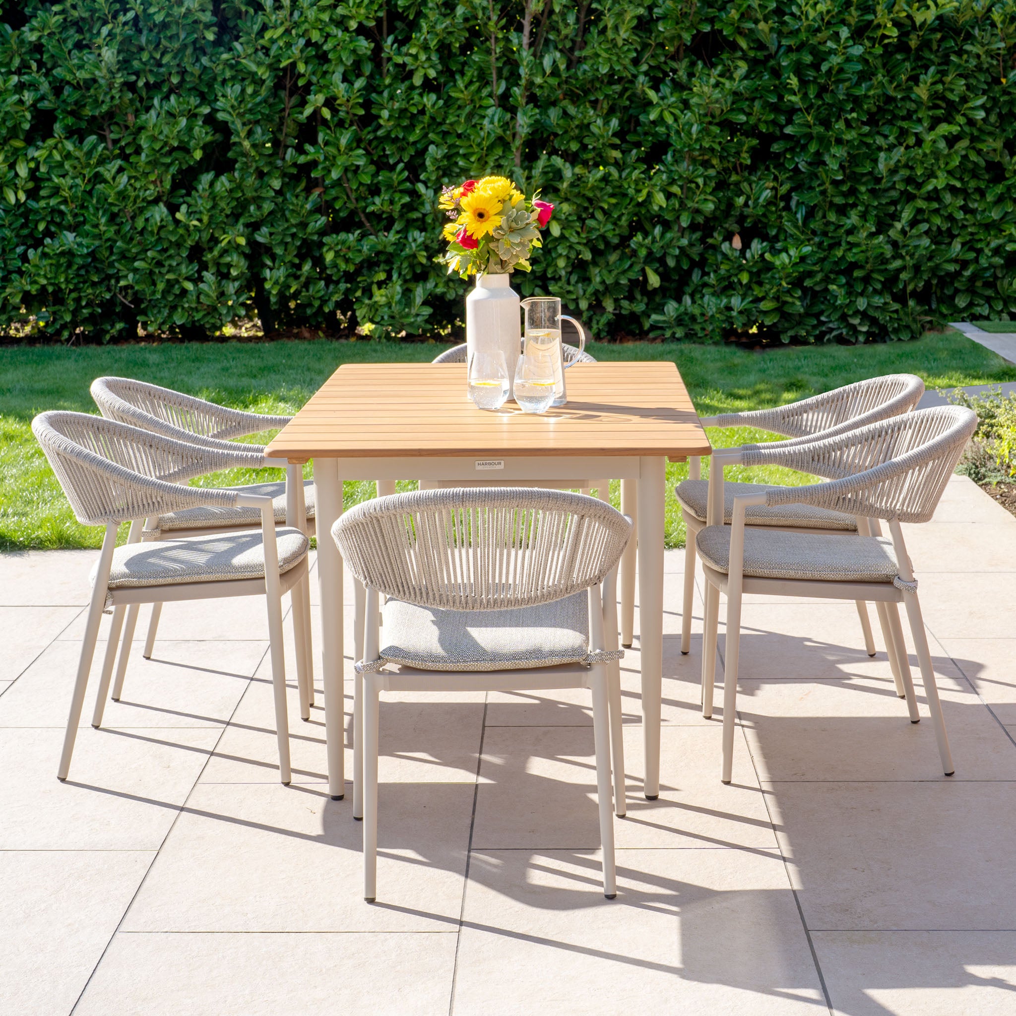 The Cloverly 6 Seat Rectangular Dining Set in Latte features a beautifully crafted teak table, complemented by a sophisticated aluminum frame, making it an ideal choice for any patio setting.