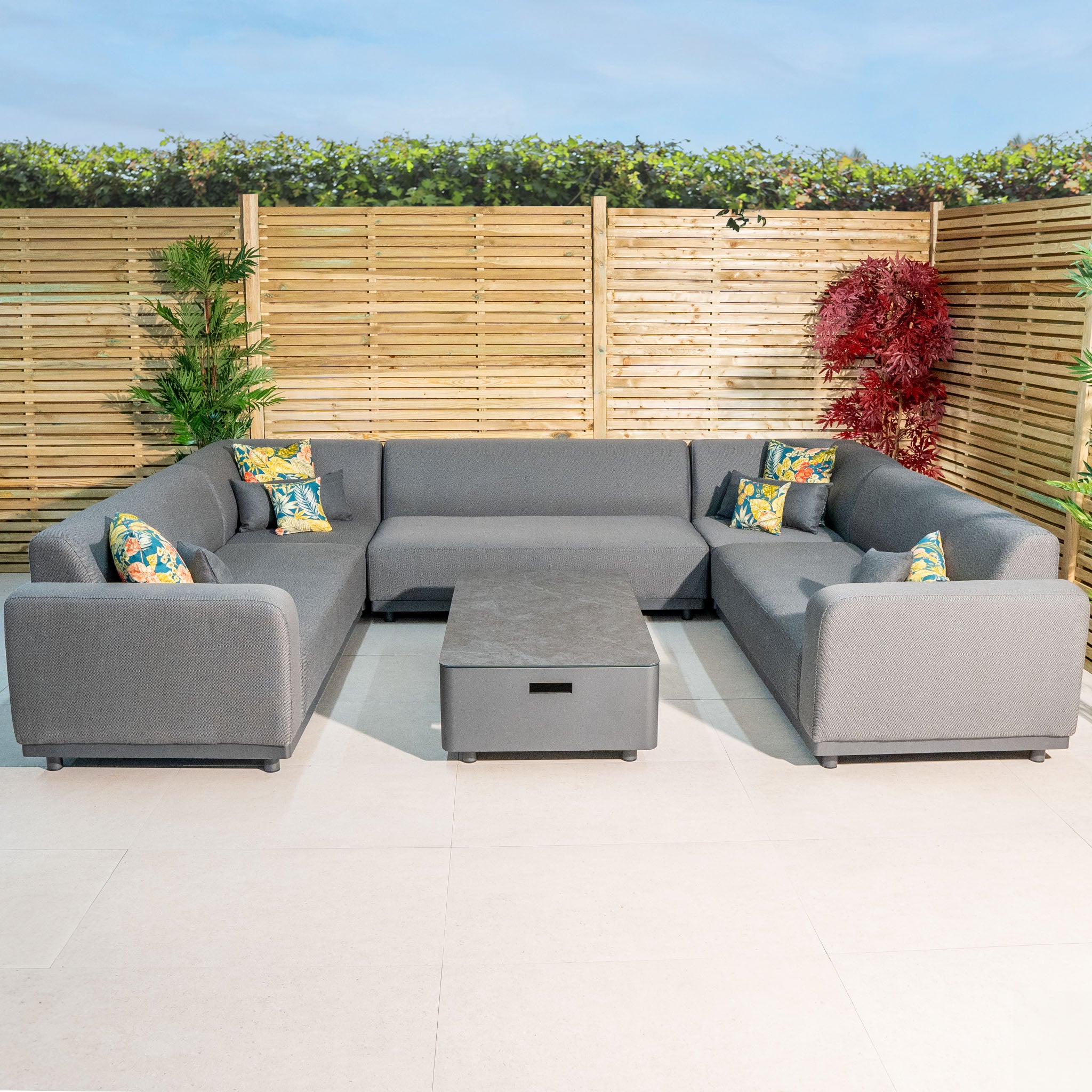 Outdoor seating area featuring the Luna U-Shape Outdoor Fabric Sofa Set with Coffee Table in Grey, complemented by decorative throw pillows.