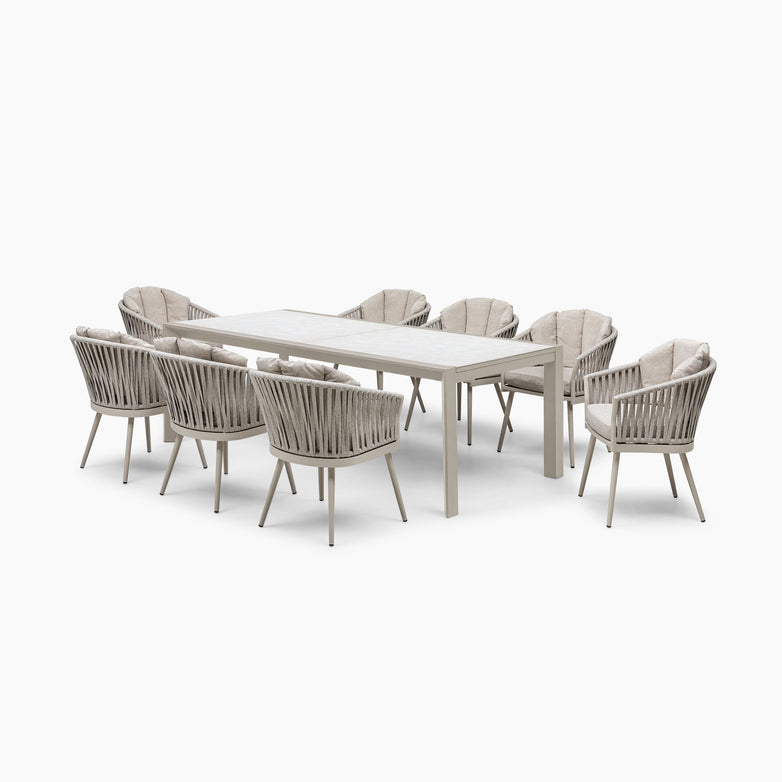 The Monterrey 8 Seat Rope Extending Dining Set in Latte includes a rectangular outdoor table with eight cushioned chairs made from hydrophobic rope, upholstered in durable Olefin fabric, all on a pristine white background.