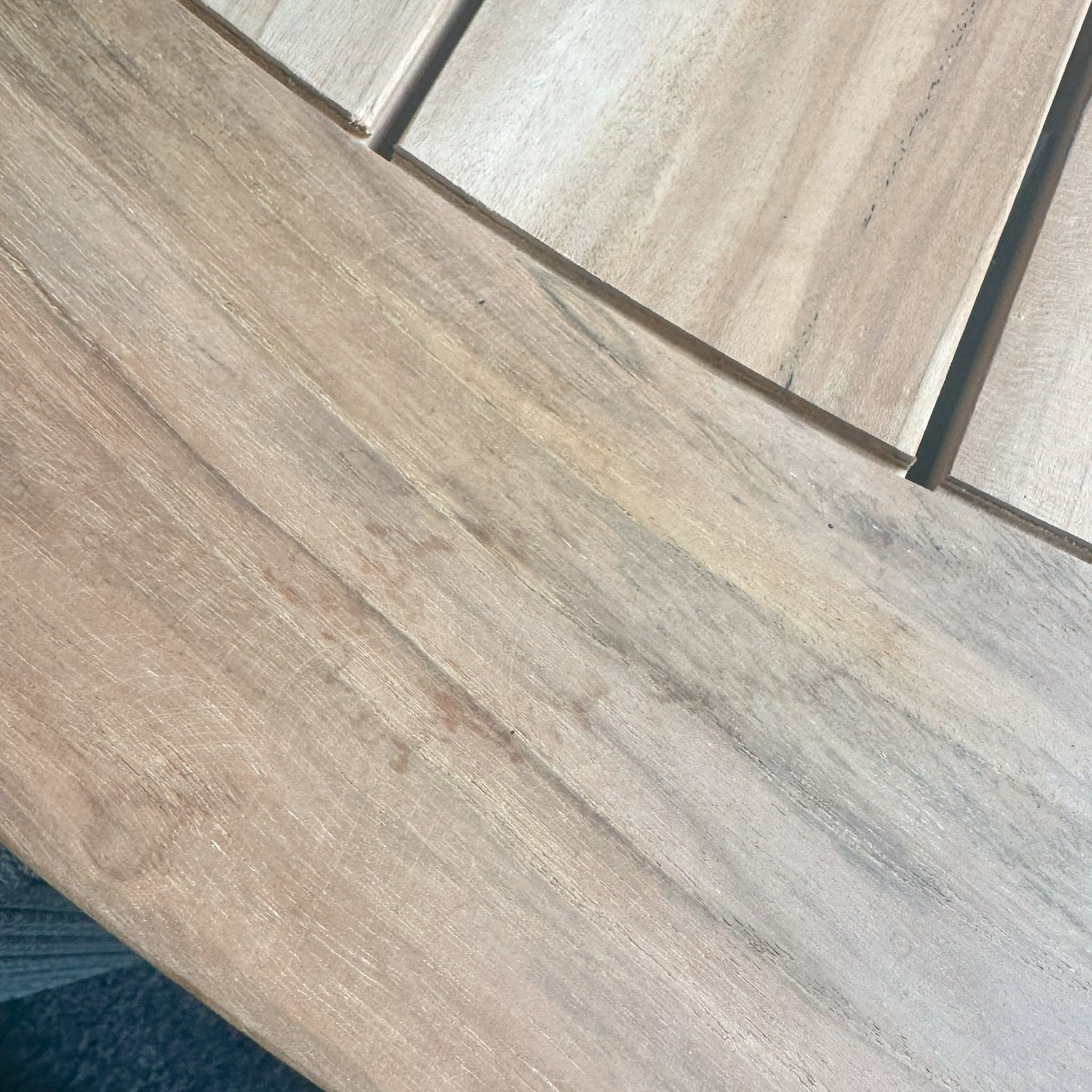 Close-up of a wooden table with visible grain patterns, showcasing the smooth surface and intricate joinery lines from the Bernini 6 Seat Round Dining with Teak Table in Light Grey (Ex Display).