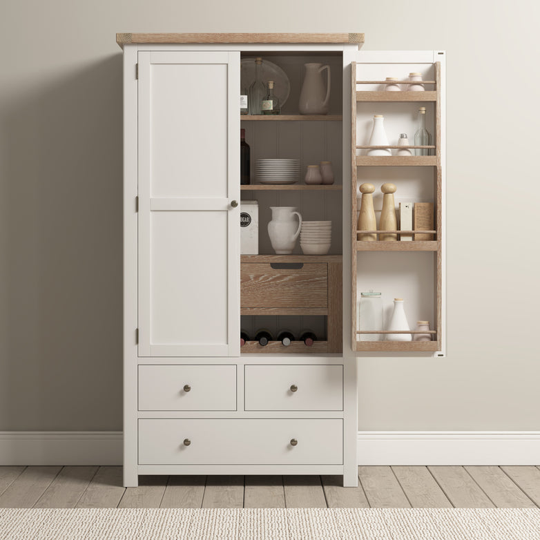 The Burford Double Larder Unit in Warm White features a natural oak design with a white cabinet, showcasing an open door that reveals kitchenware and condiments. It offers perfect storage and organization with its three drawers at the bottom, all beautifully set on a wooden floor.