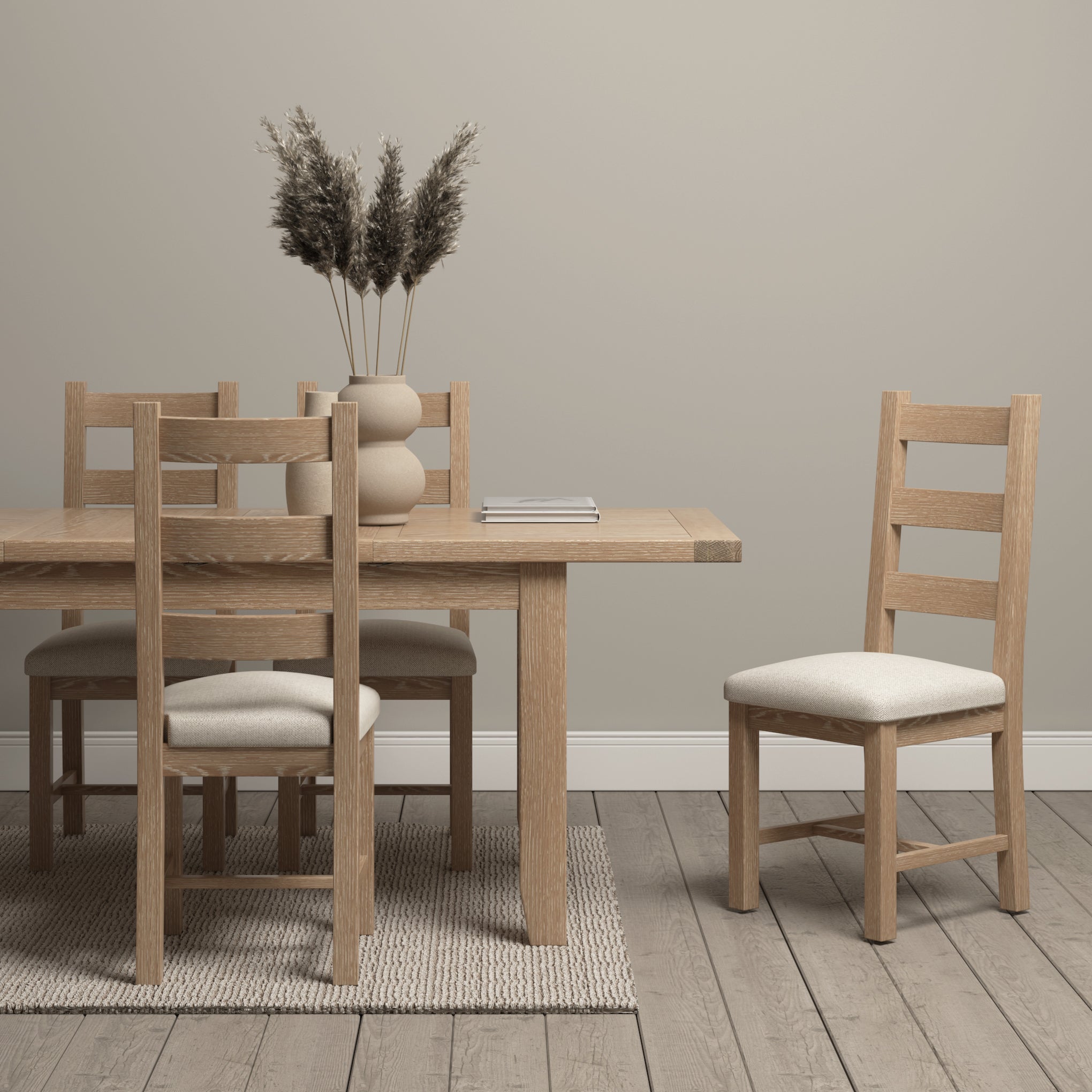 A minimalist dining room showcases the Burford 6-10 Seater Extending Dining Table in Natural Oak, accented by upholstered chairs and pampas grass-filled vases, all set on a light wood floor.