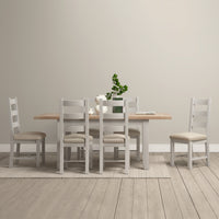 Minimalist dining room showcasing an elegant Burford 4-6 Seater Extending Dining Table in pebble grey, accompanied by six chairs and a potted plant centerpiece on a light-colored rug.