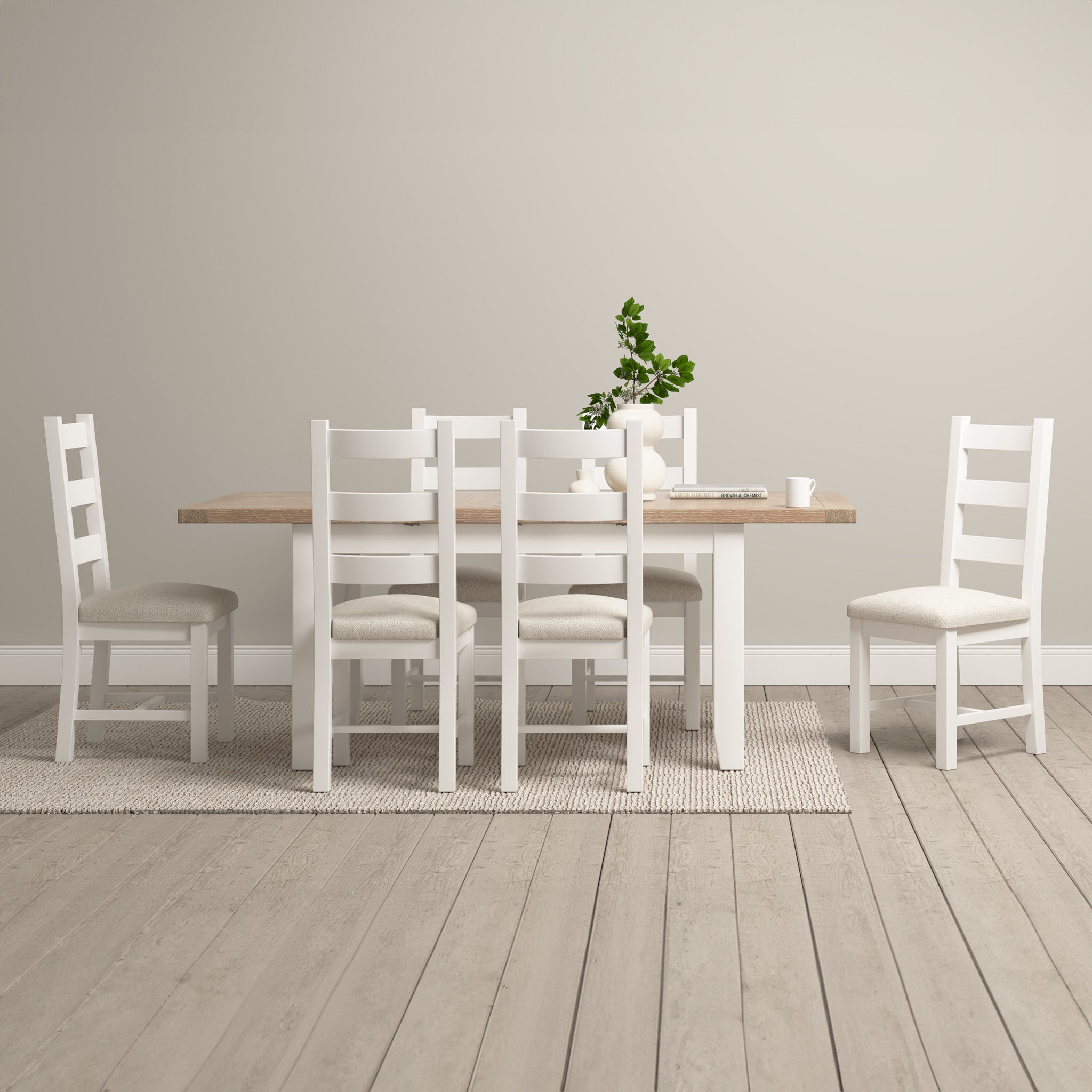 A dining room exuding contemporary elegance with a Burford 4-6 Seater Extending Dining Table in Warm White, accompanied by six white chairs and a green plant adorning the light wood floor.