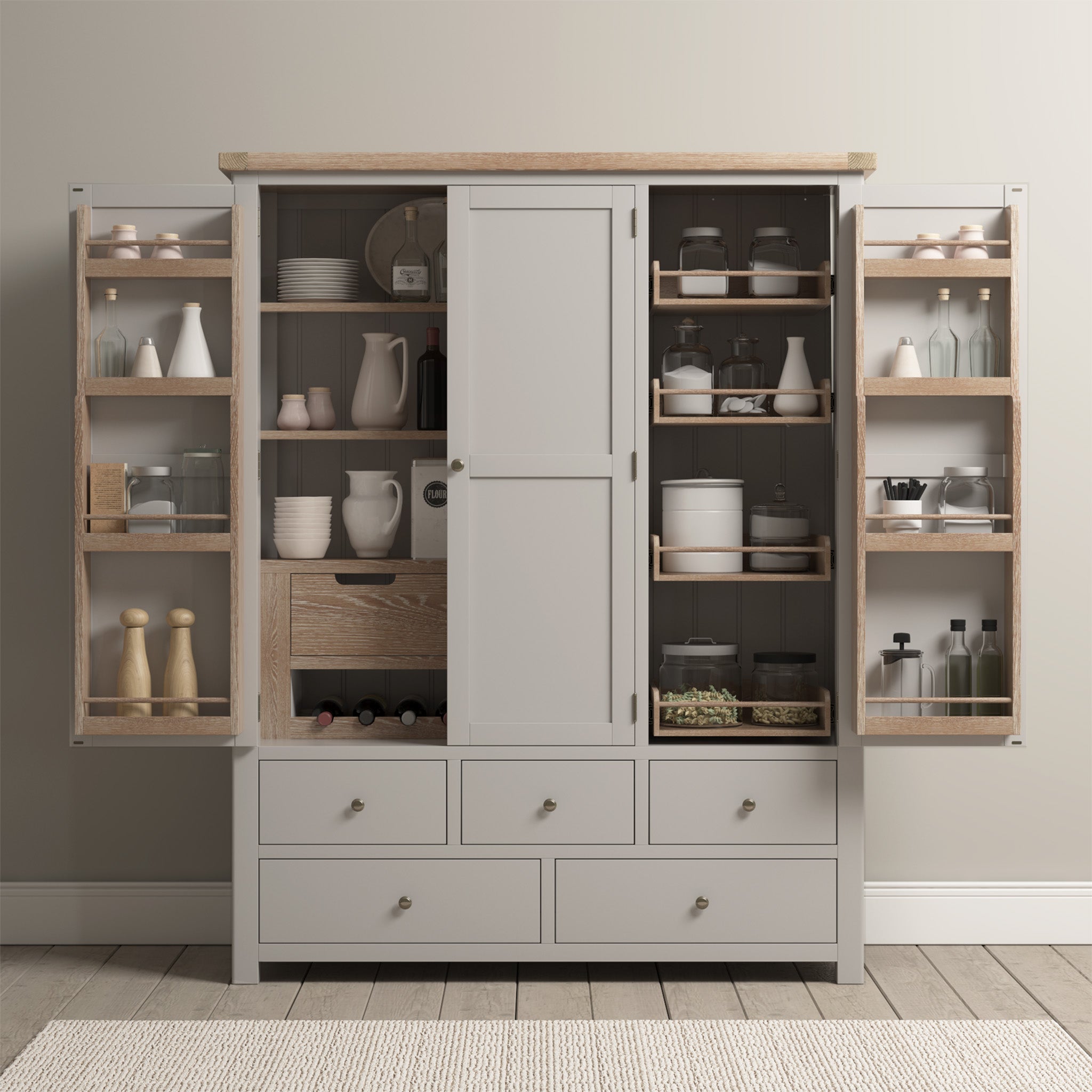 Open pantry cupboard with neatly organized jars, bottles, and kitchenware on shelves and drawers. Experience ultimate kitchen storage solutions with the Burford Triple Larder Unit in Pebble Grey, crafted from natural oak for a touch of elegance and functionality.