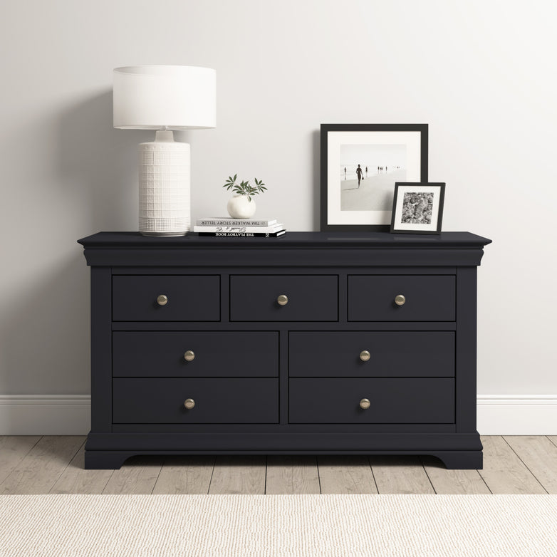 Dusky Black Chalbury 3 Over 4 Chest of Drawers adorned with a white lamp, books, and framed photos against a light wall.