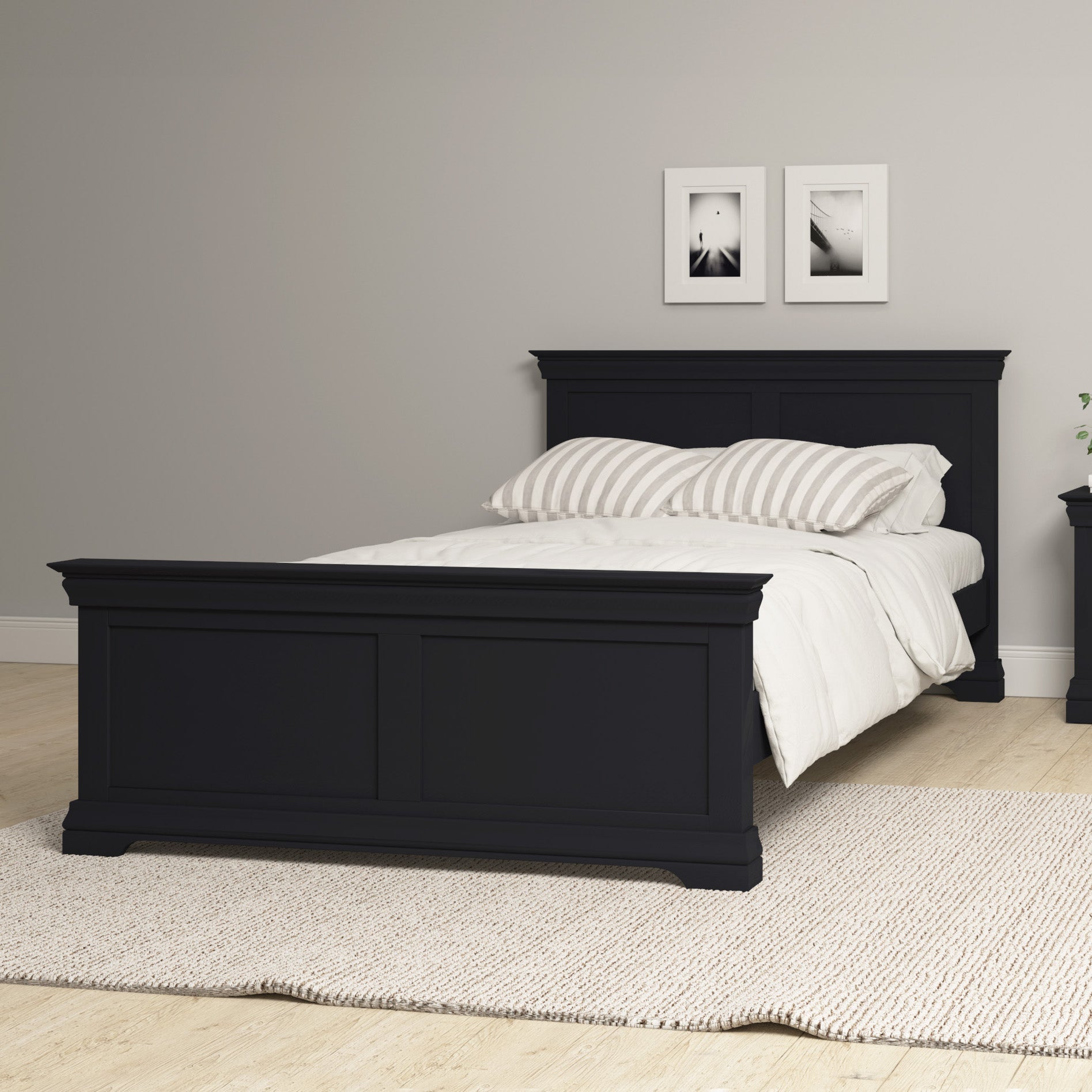 A Chalbury 5ft High-End Kingsize Bed Frame in dusky black, complete with striped pillows, elegantly enhances a minimalist room decorated with wall art and a beige rug.