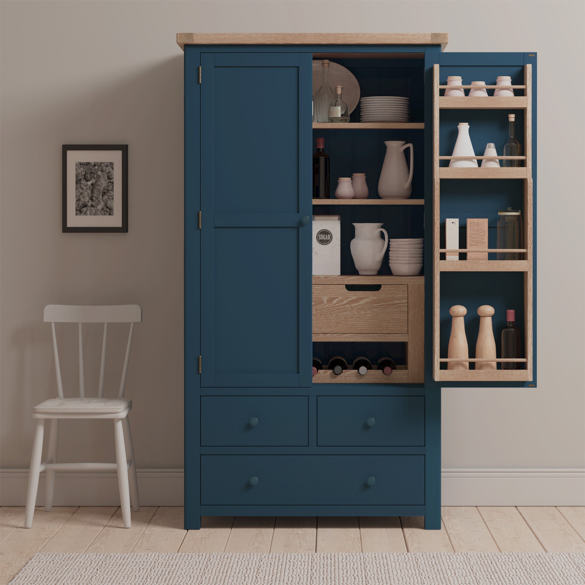 The Burford Double Larder Unit in Navy Blue, with its open doors, unveils shelves filled with dishes and condiments, positioned beside a chair and a framed picture.