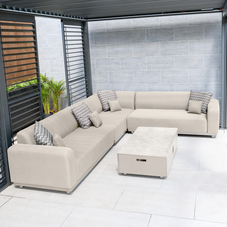 An outdoor seating area features the Luna Outdoor Fabric Large Corner Group Set in Fawn, complete with patterned cushions and a maintenance-free rectangular coffee table on the tiled floor, creating an inviting and durable space for all-weather enjoyment.