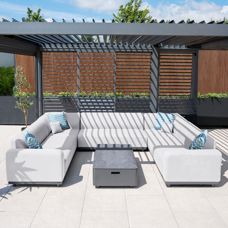 Modern outdoor patio with the Luna U-Shape Outdoor Fabric Sofa Set in Oyster Grey, including all-weather proof design, blue and white throw pillows, a square coffee table, and slatted pergola, featuring quick dry foam cushions.