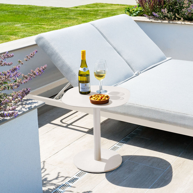 The Luna Range outdoor lounge features a weatherproof cushioned chair and the elegant 45cm x 45cm Luna Side Table in Latte, perfectly set with a wine bottle, glass, and snacks on the sunlit patio.