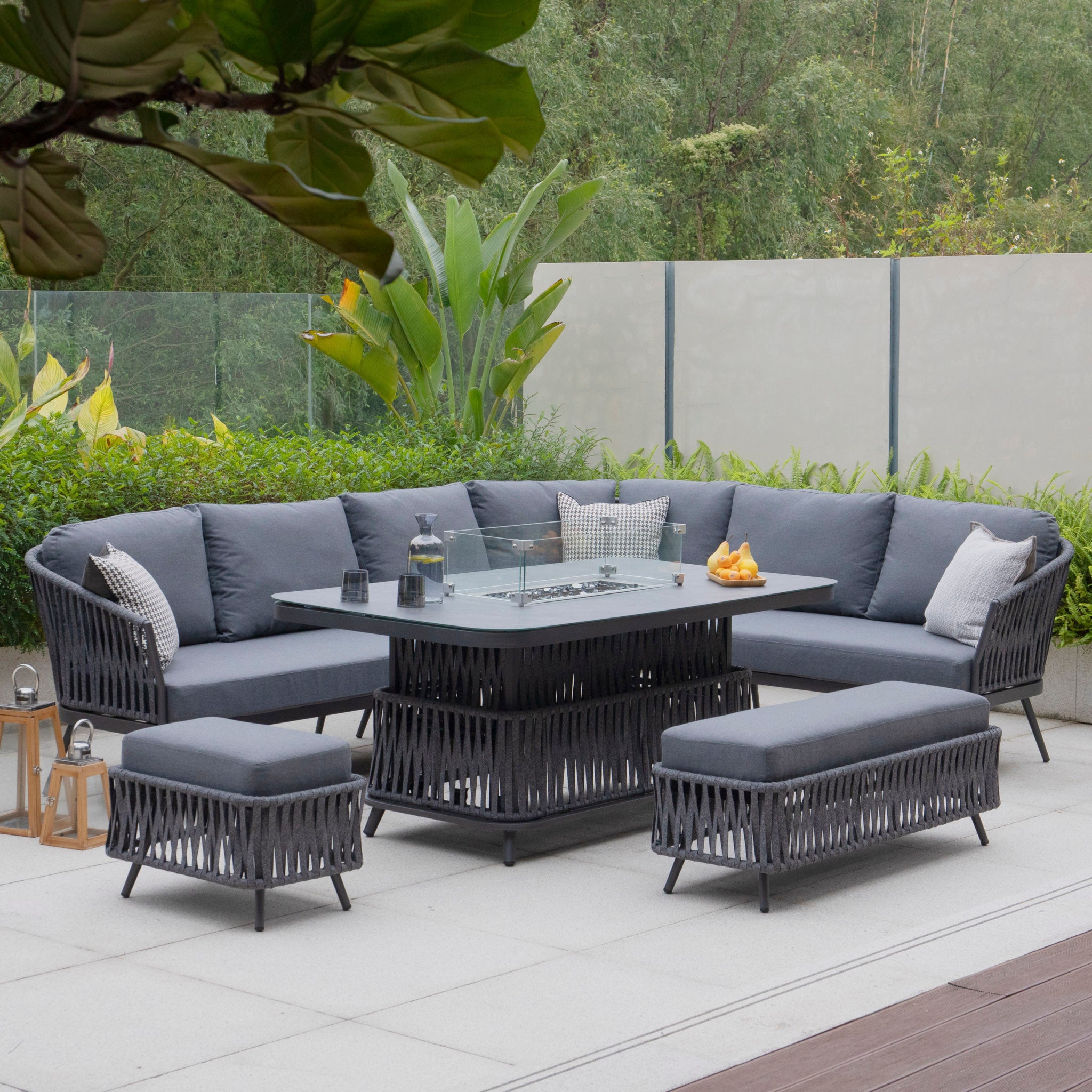 Monterrey Rope Rectangular Corner Dining Set from the Monterrey Range, featuring a right-hand corner sectional sofa, a rising firepit table, and two ottomans, all in dark gray wicker and cushions.