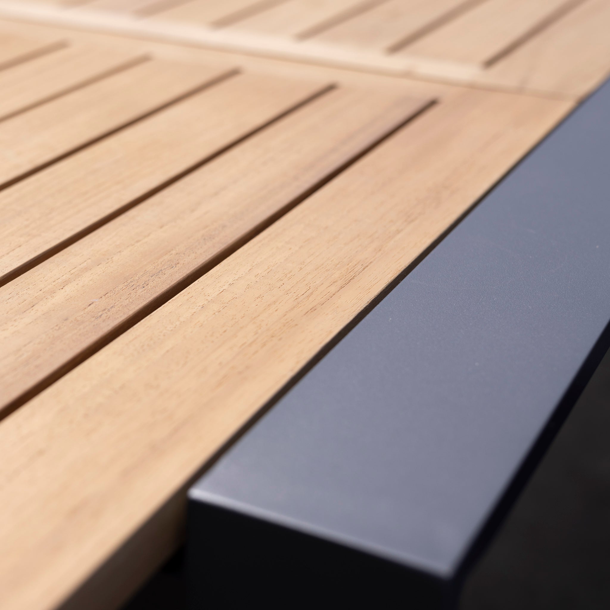 Close-up view of the Monterrey 10 Seat Rope Extending Teak Dining Set in Grey, featuring a teak extending table with a dark gray metal edge beautifully complemented by Monterrey chairs.