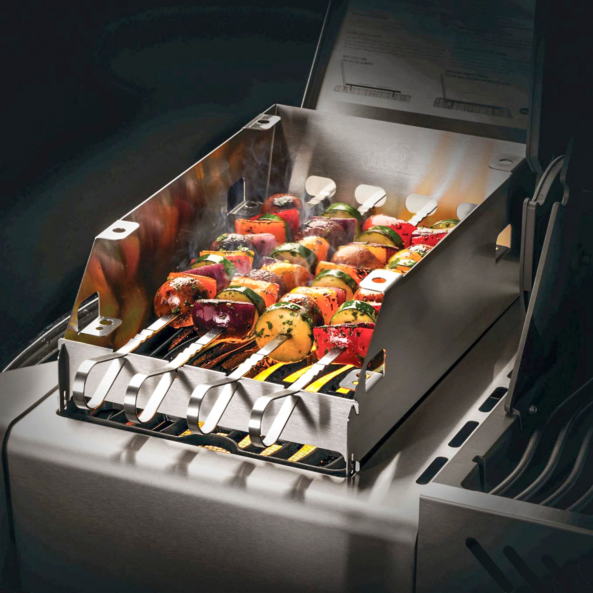 Skewers of mixed vegetables and meat grill to perfection on the Napoleon Rogue barbecue, utilizing stainless steel skewers under the lid, with steam rising up around the Napoleon Side Burner Windshield - Large.