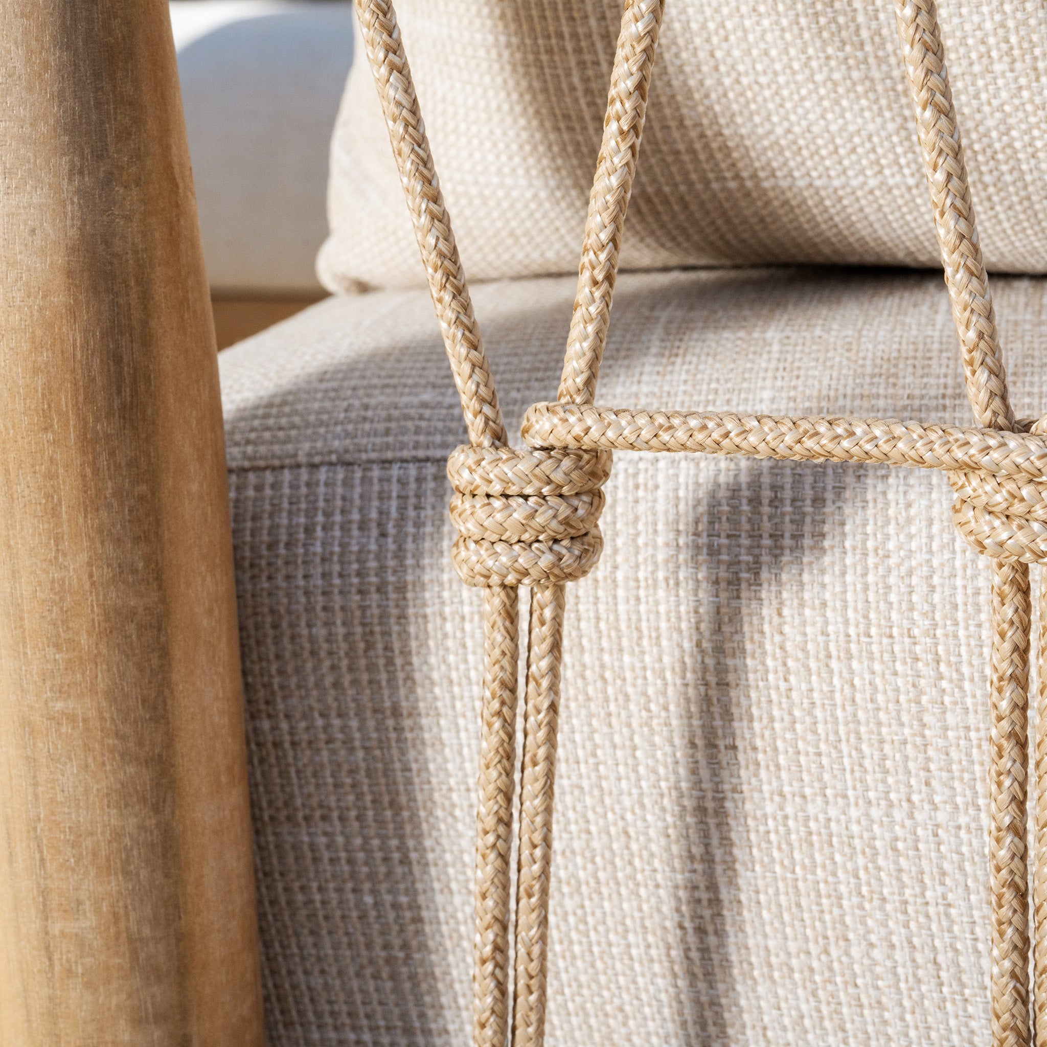 Close-up of beige woven ropes and beige upholstery on the Paia 3 Seat Sofa Set in Linen, set on a wooden chair frame with a bright, soft background, perfect for outdoor seating in your garden. The water-resistant polyester ensures durability and style.