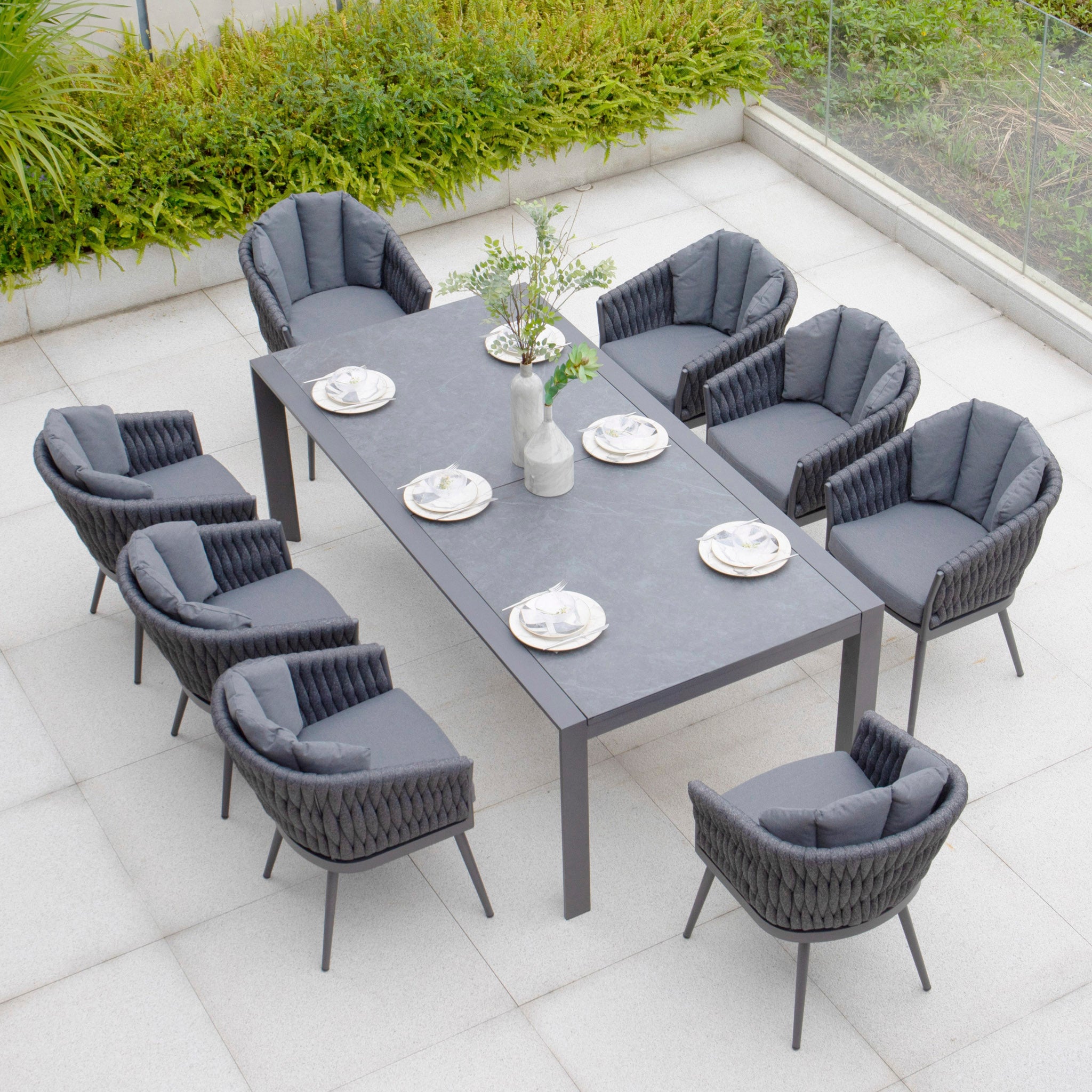 Discover the Harbour Lifestyle Palma 8 Seat Rope Extending Dining Set in Grey, featuring a high-quality aluminium construction, a rectangular table, eight cushioned chairs, and a tableware set on a tiled patio.