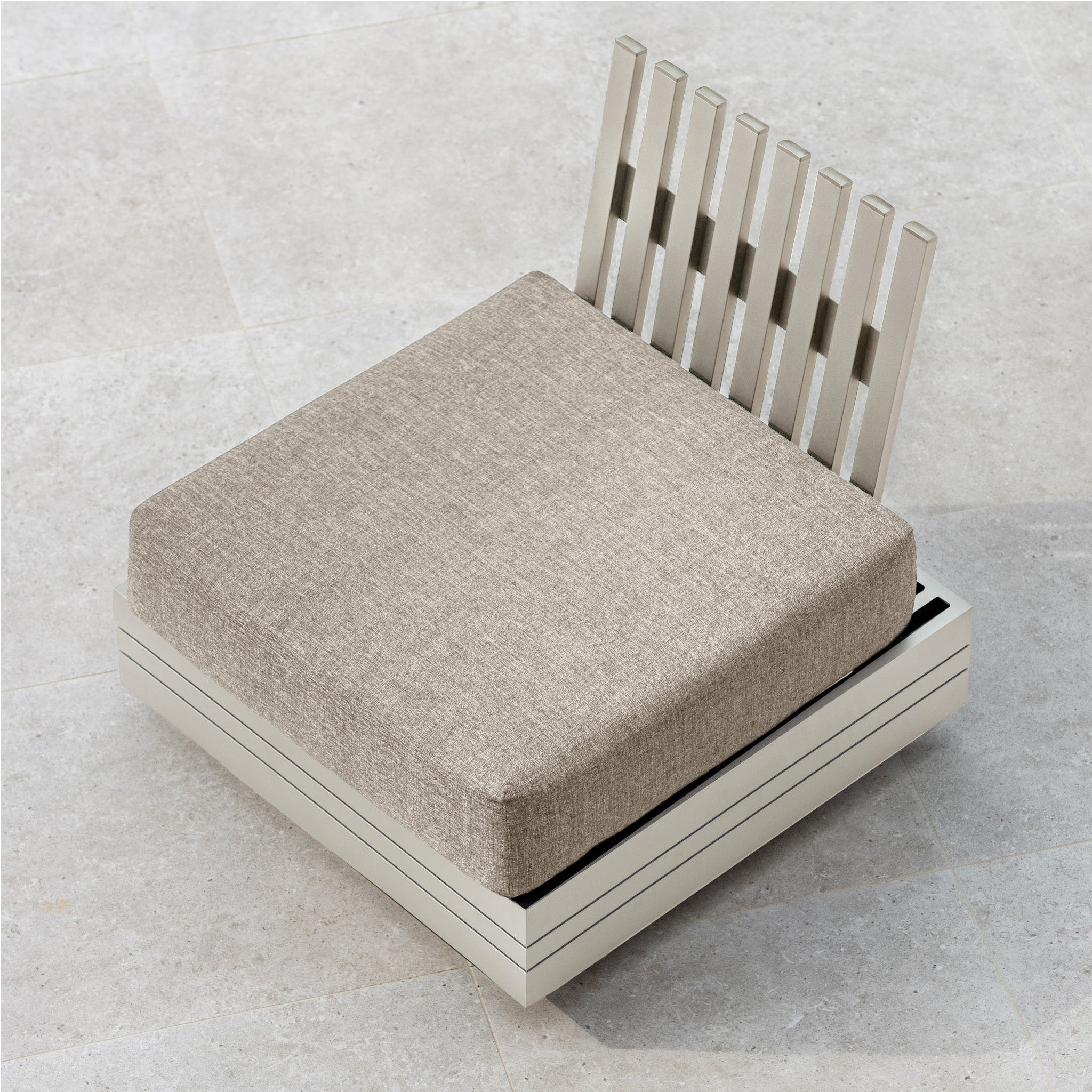 The Panama Corner Unit/Footstool in Latte, featuring a rectangular beige cushion and a vertical slatted backrest, is positioned in front of a modular system on a light-colored tiled floor.