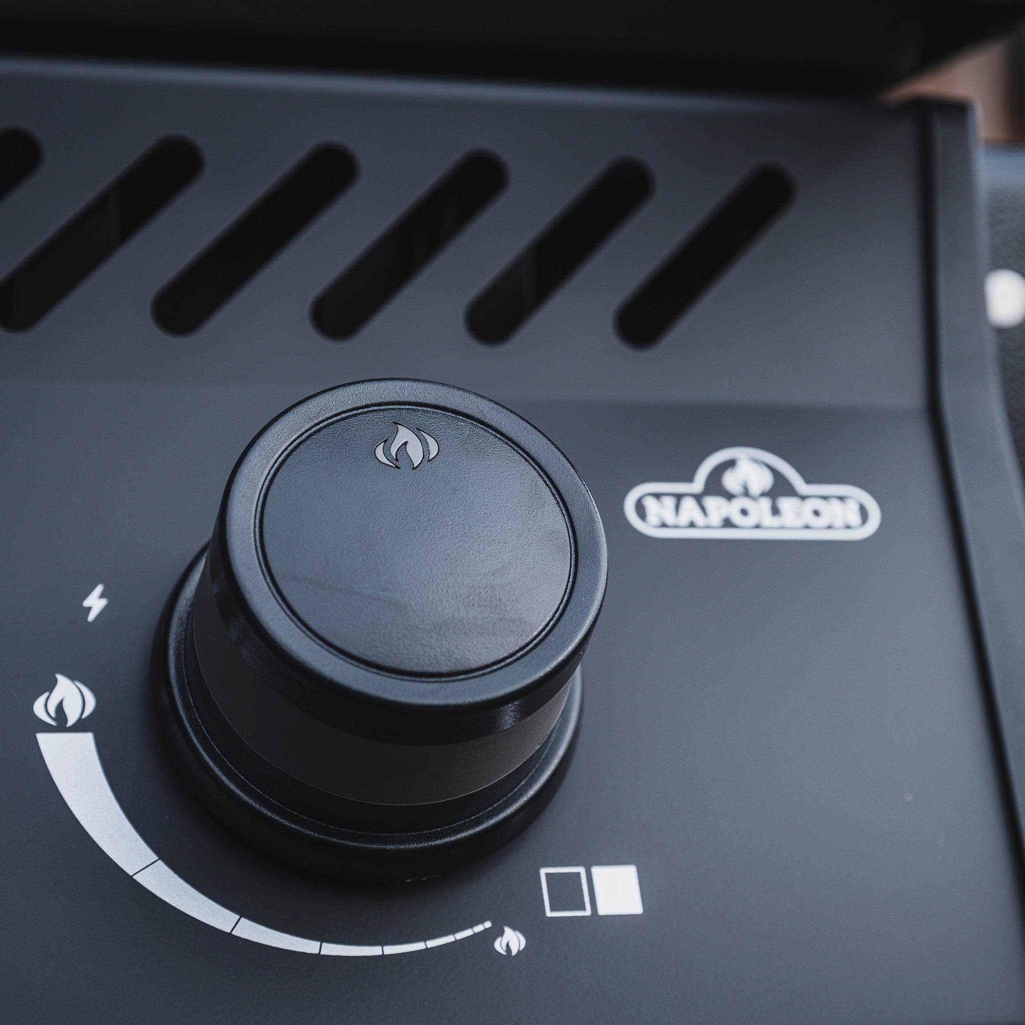 Close-up of a black control knob on the Napoleon Rogue 525 Gas Barbecue, with flame and temperature settings visible, showcasing the precise temperature control of this propane gas grill.