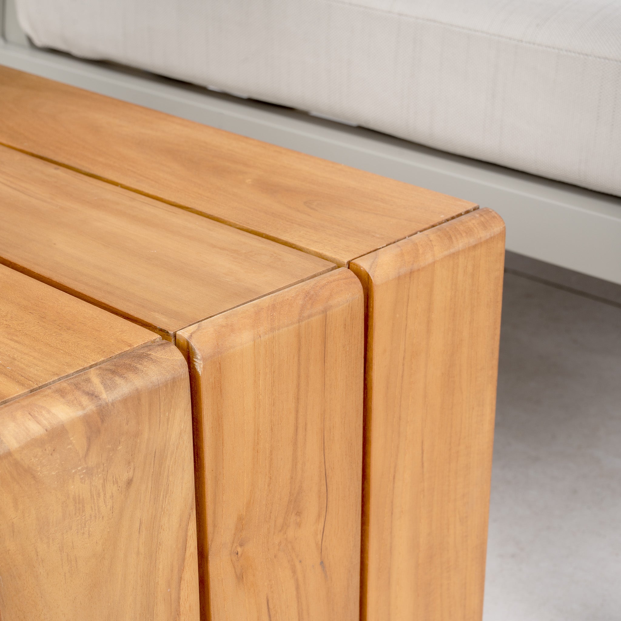 Close-up of the Stockholm Corner Dining Set featuring a firepit table in limestone with a smooth finish, accompanied by weatherproof cushions in the background.