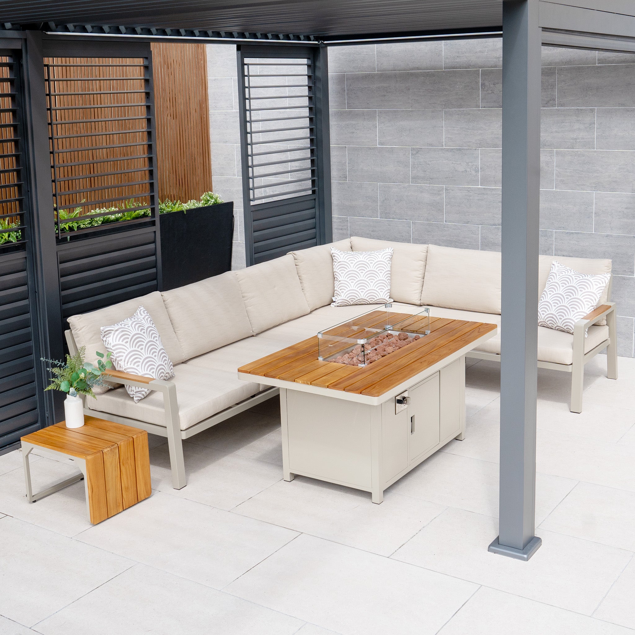 Modern outdoor patio featuring the Stockholm Corner Dining Set with Firepit Table in Limestone, complemented by a wooden coffee table, all situated under a pergola.