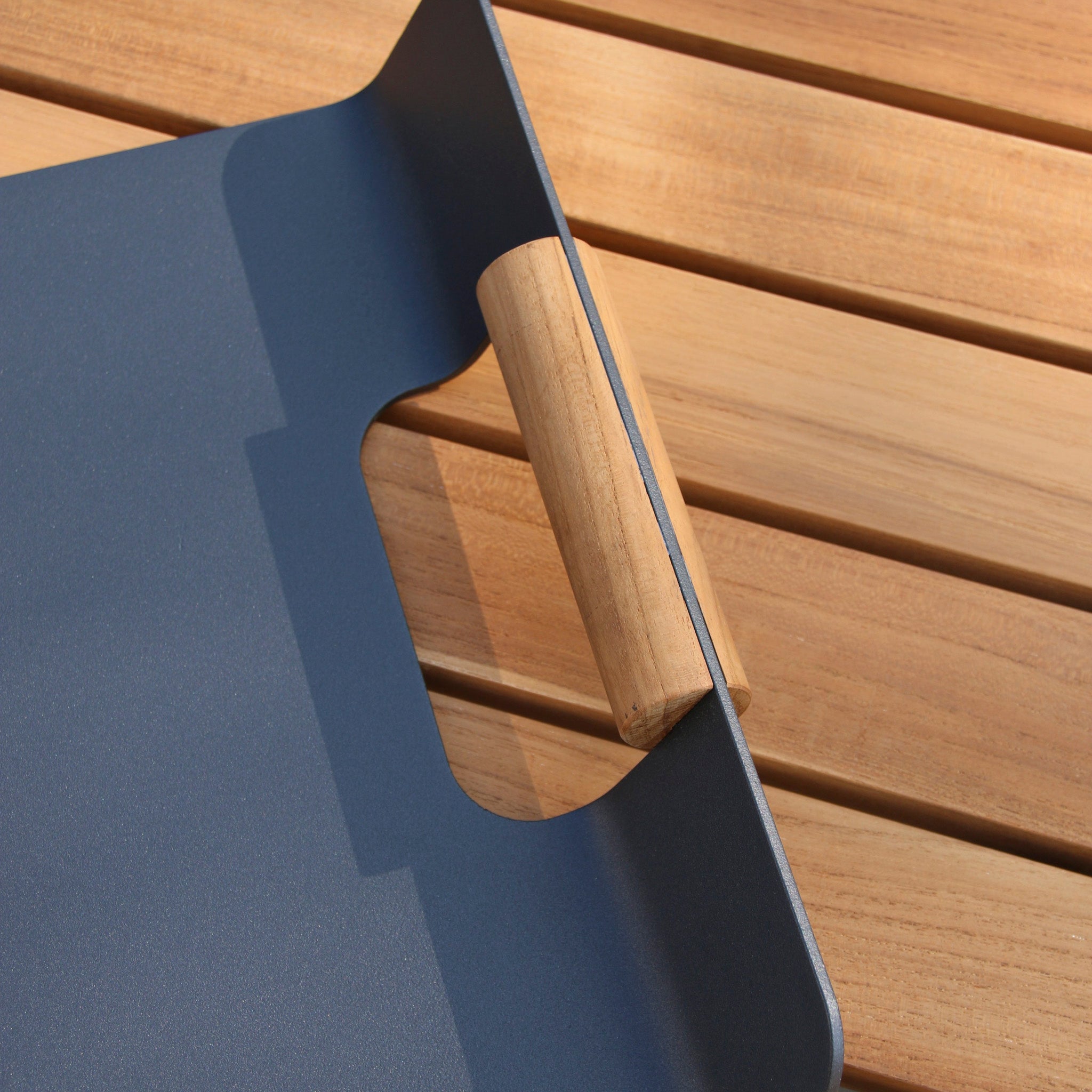 Close-up of a Tracy Serving Tray with Teak Handles in Charcoal, placed on teak garden furniture.