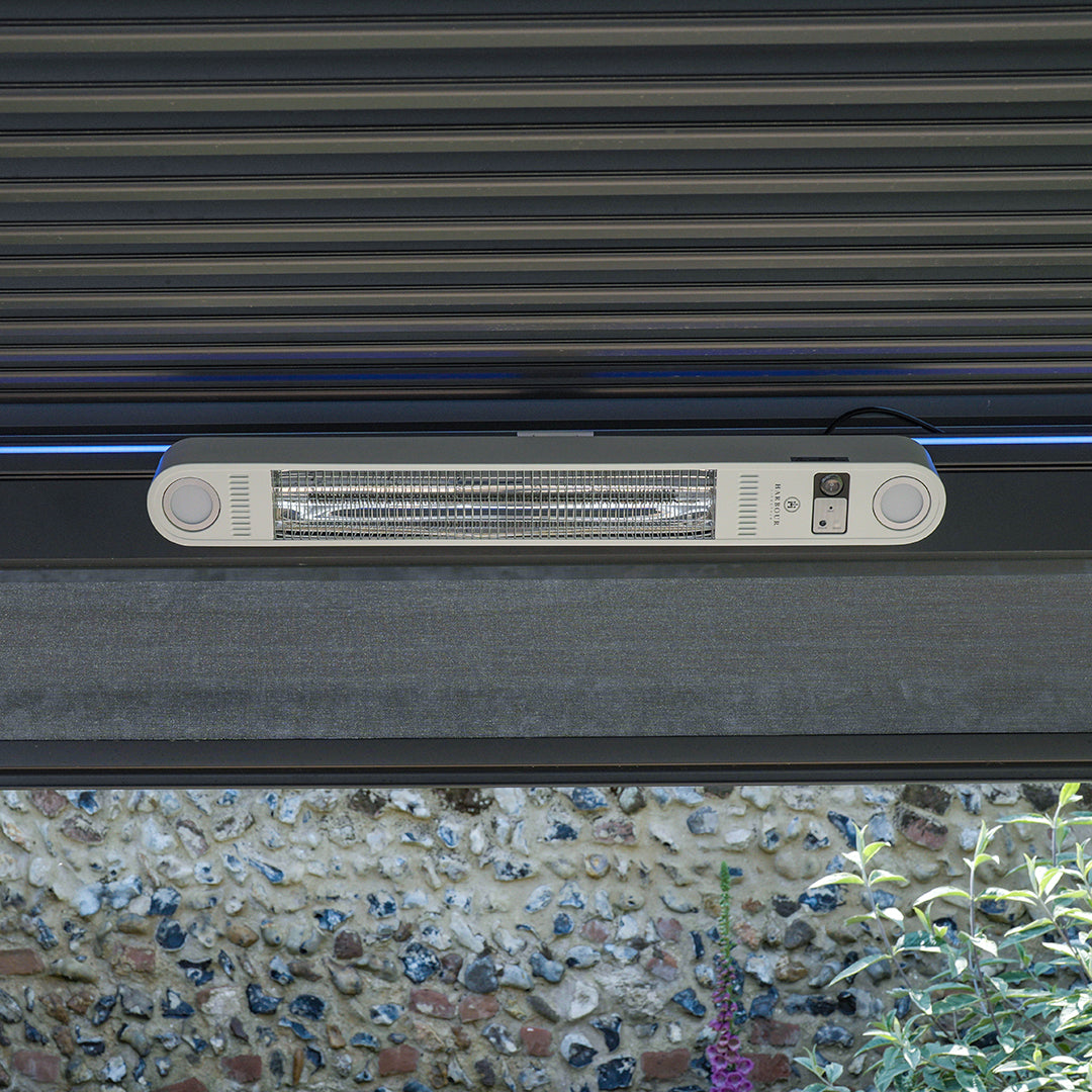 The FREE PergoSTET Wifi & Bluetooth Heater in White, ceiling-mounted with a metal grate, is expertly designed as an outdoor heating solution against a stone wall. Ideal for pergola ceiling installations, it also features remote-controlled functionality for effortless adjustments.