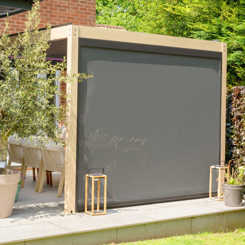 Outdoor patio area featuring a PergoSTET 3m x 3m Square Pergola with 3 Drop Sides and LED Lighting with Wood Effect covering a portion of the space, surrounded by greenery and outdoor furniture.