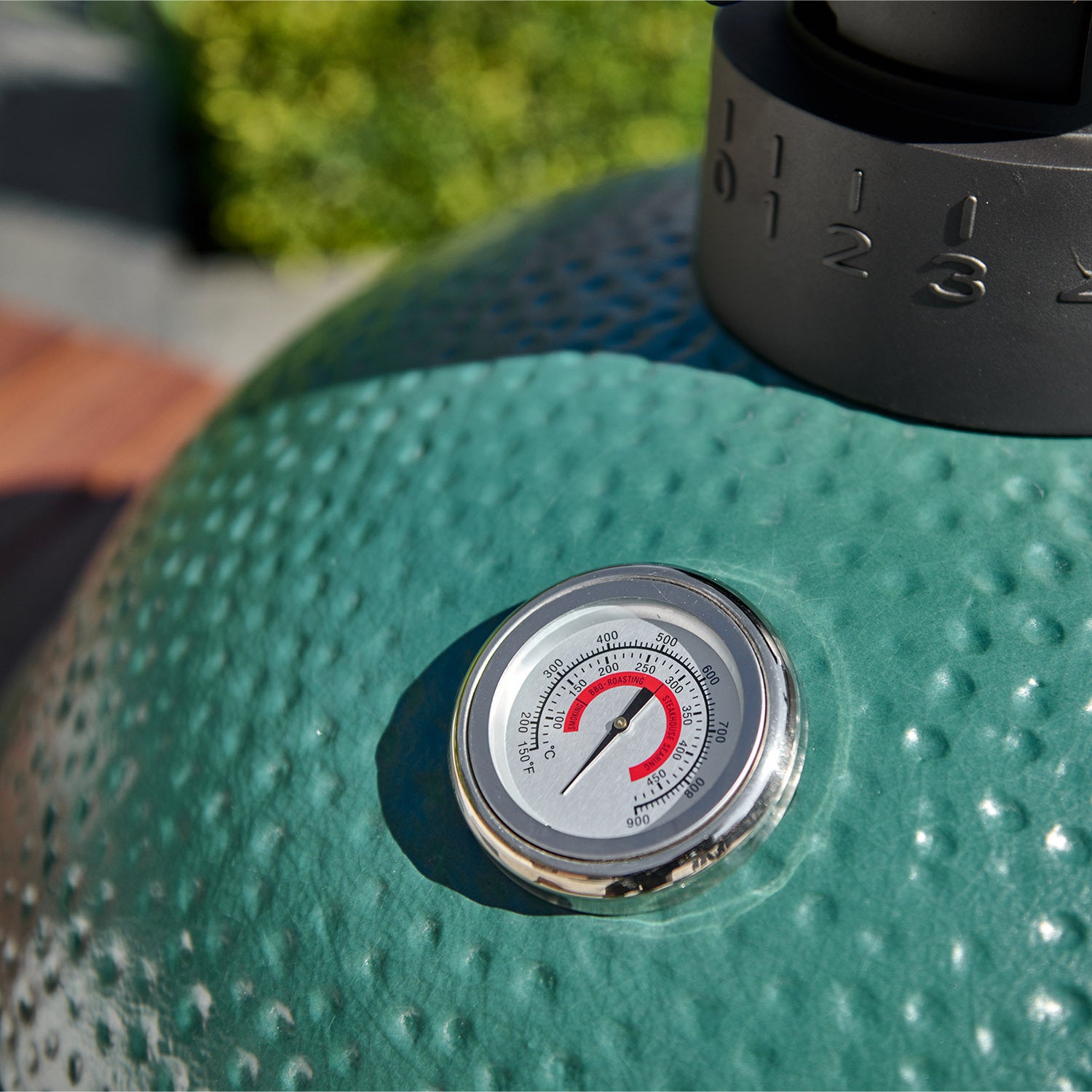 Close-up of a Kamado BBQ 18" Ceramic Grill in Matte Green with ceramic walls and a thermometer gauge displaying the temperature in both Fahrenheit and Celsius.