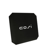 A black, square, rounded-corner object resembling a cover plate has "cosi" in white text at its center. It's the Cosi - Cover Plate Glass Set Medium.