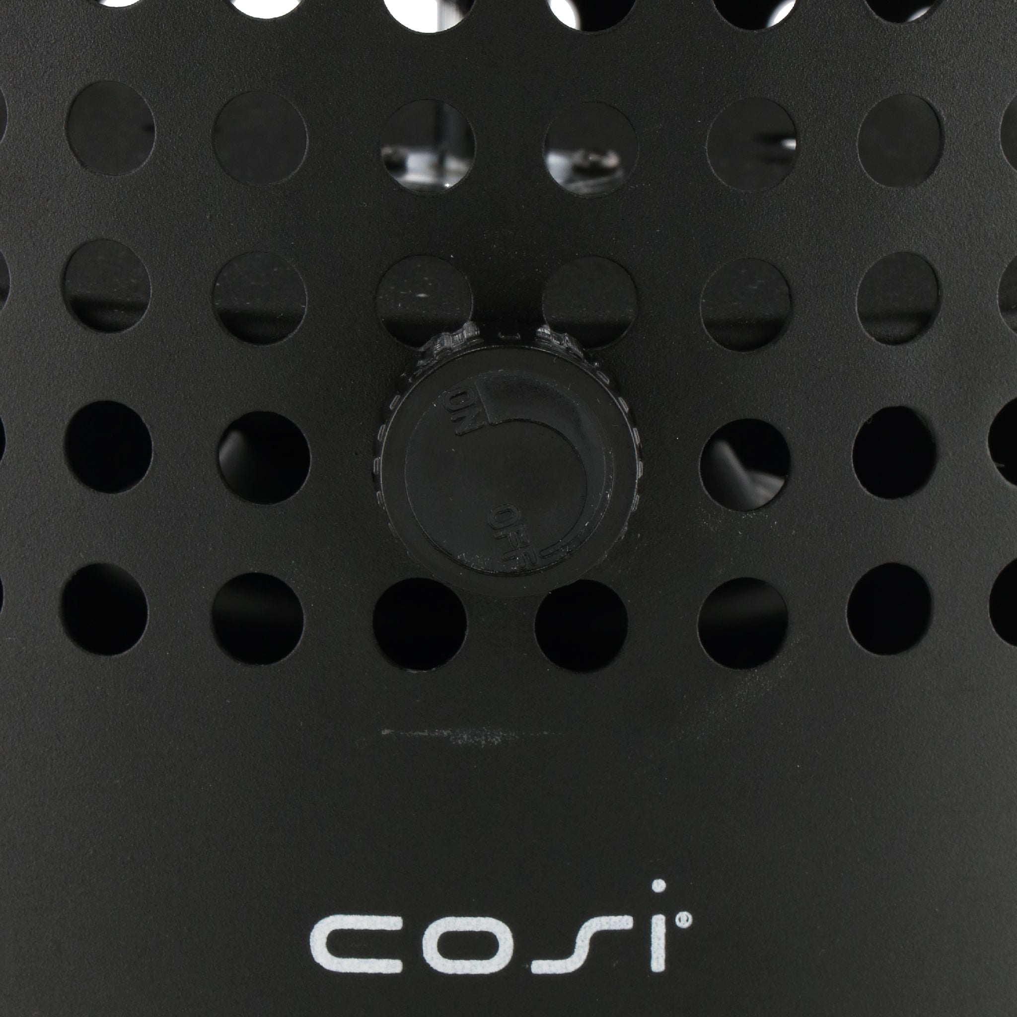 Close-up of a black perforated surface with the word "cosi" below a round knob in the center, part of the Cosiscoop Drop Lantern in Black range, perfect for any outdoor space using gas cartridges.