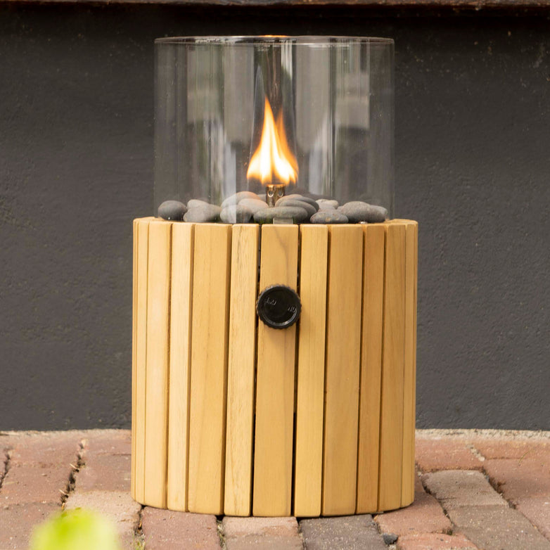 The Cosiscoop Timber Round Fire Lantern, featuring a portable tabletop design with a clear glass enclosure and wooden slatted base, adds elegance to any setting with its small flame, serving as both a decorative piece and functional garden lantern.