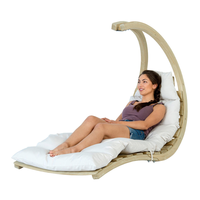 A woman relaxes on a Swing Lounger in Creme, appreciating the ideal combination of comfort and sophistication.