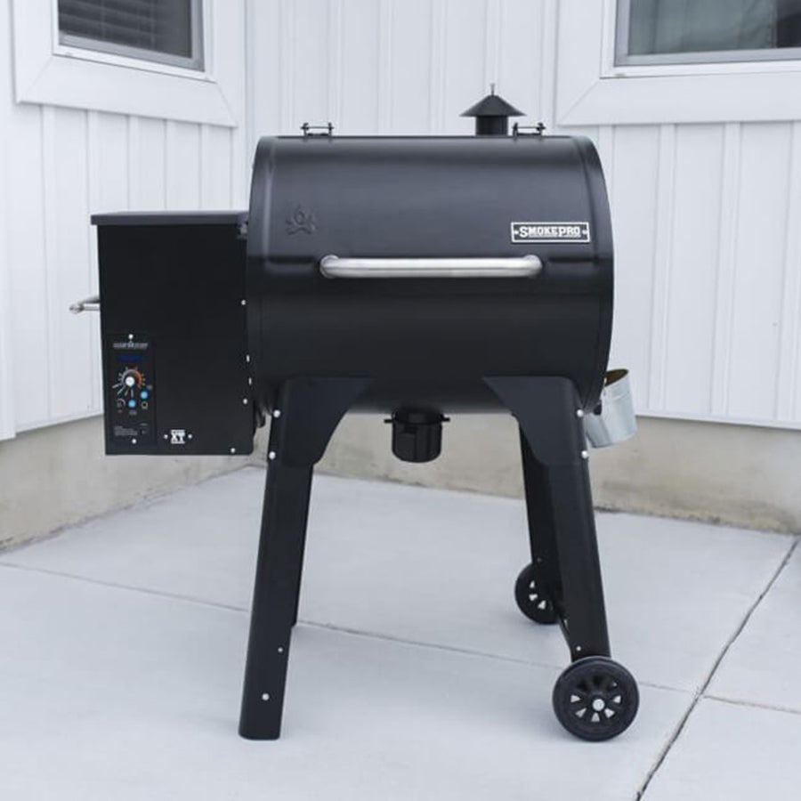 Camp Chef XT 24 Pellet Grill with Smart Smoke Technology on a concrete patio against a white siding wall.