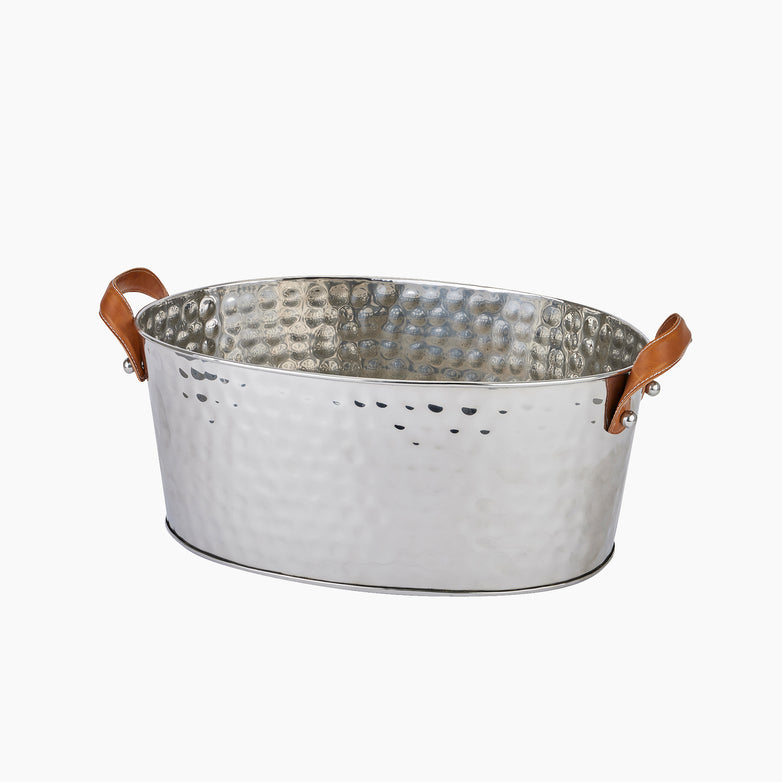 The Silver Large Leather Handled Champagne Cooler, an oval-shaped hammered tin bucket featuring high-quality leather handles on both sides, is perfect for chilling champagne against a white background.